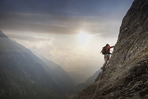 Climber scaling face of a mountain